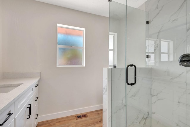 full bath with a marble finish shower, vanity, and baseboards