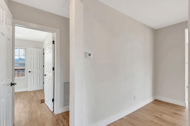 hall with light wood-type flooring and baseboards
