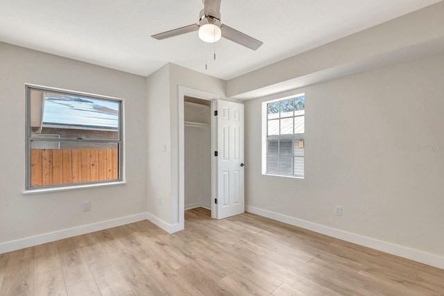 unfurnished bedroom featuring baseboards, light wood-type flooring, ceiling fan, and a closet