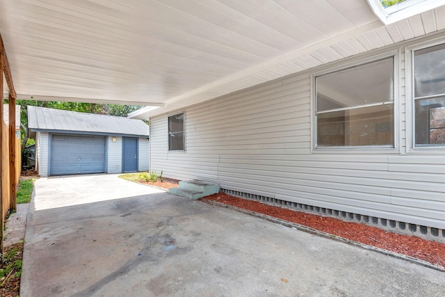 view of side of home featuring an outdoor structure, a garage, and driveway