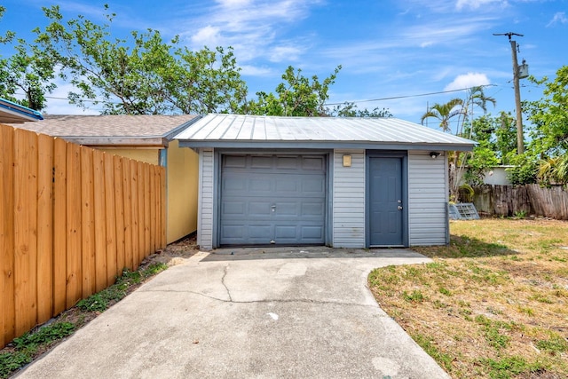 detached garage with fence and concrete driveway