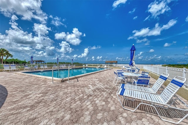 community pool with fence and a patio area