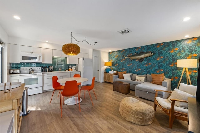 205 71st St Unit B, Holmes Beach, FL 34217 - living room featuring wallpapered walls, light wood-style floors, an accent wall, and recessed lighting