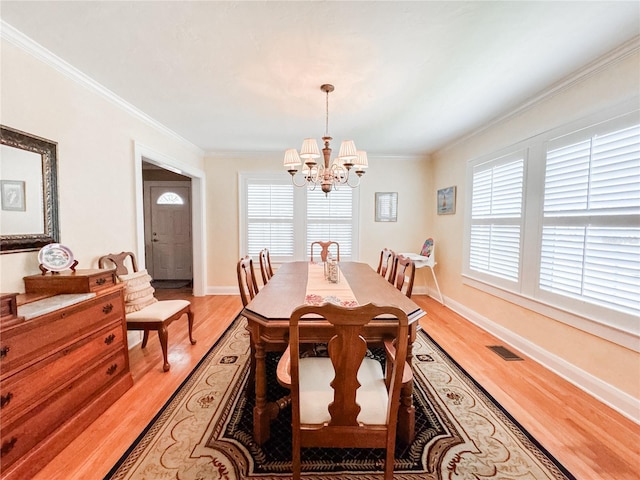 dining area featuring a chandelier, crown molding, light wood-style floors, and baseboards