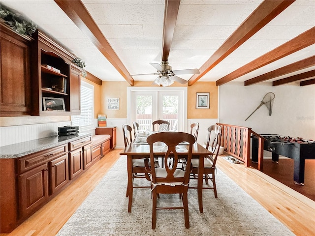 dining space featuring beam ceiling, light wood-style floors, and a ceiling fan