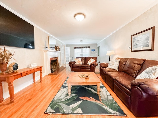 living room with wood finished floors, crown molding, and a fireplace with raised hearth