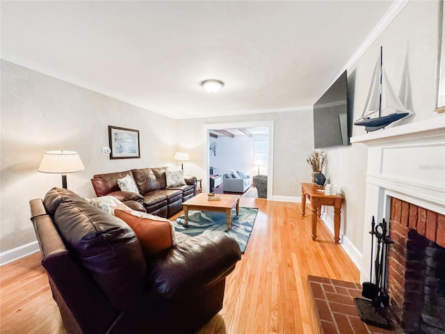living area with a fireplace, light wood-style flooring, crown molding, and baseboards