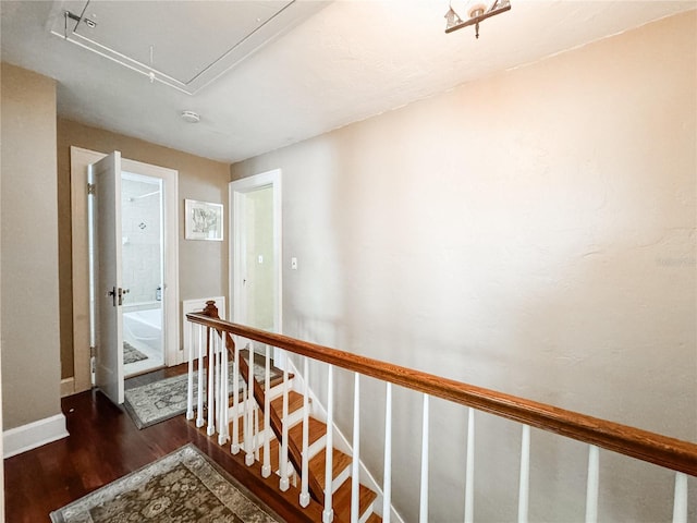 hall featuring attic access, wood finished floors, an upstairs landing, and baseboards