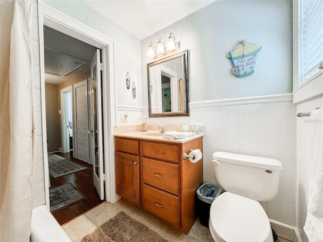 bathroom featuring a wainscoted wall, vanity, toilet, and tile patterned flooring