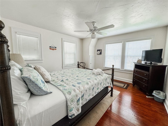 bedroom with multiple windows, dark wood-style floors, baseboards, and ceiling fan