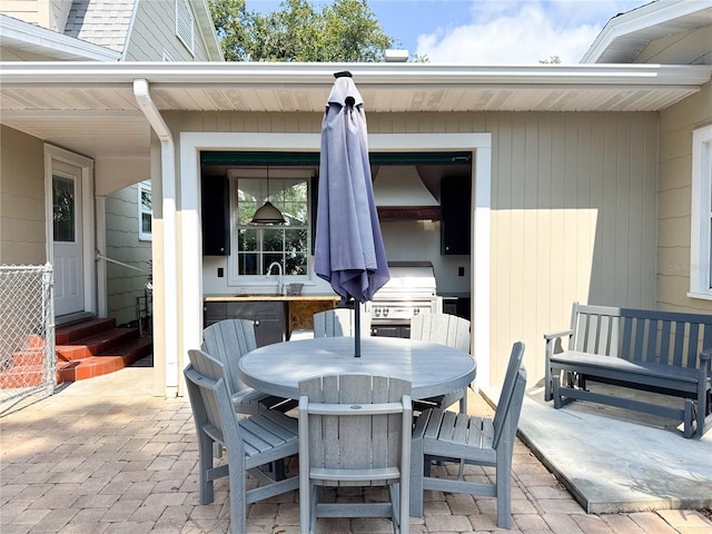 view of patio with a sink, entry steps, outdoor dining space, and a grill