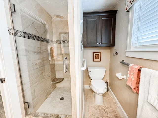 bathroom with a shower stall, toilet, baseboards, and tile patterned flooring