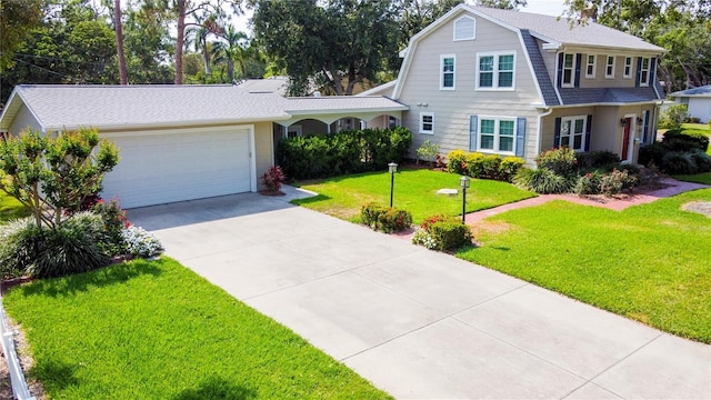 708 32nd St W, Bradenton, FL 34205 - colonial inspired home featuring a gambrel roof, a garage, driveway, a front lawn, and a shingled roof