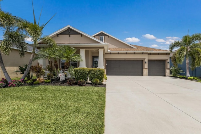 11513 11th Ave E, Bradenton, FL 34212 - view of front of house featuring an attached garage, stucco siding, a front yard, driveway, and covered porch