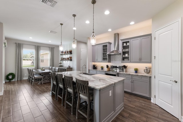11513 11th Ave E, Bradenton, FL 34212 - kitchen featuring gray cabinets, wall chimney exhaust hood, electric range, a center island with sink, and tasteful backsplash