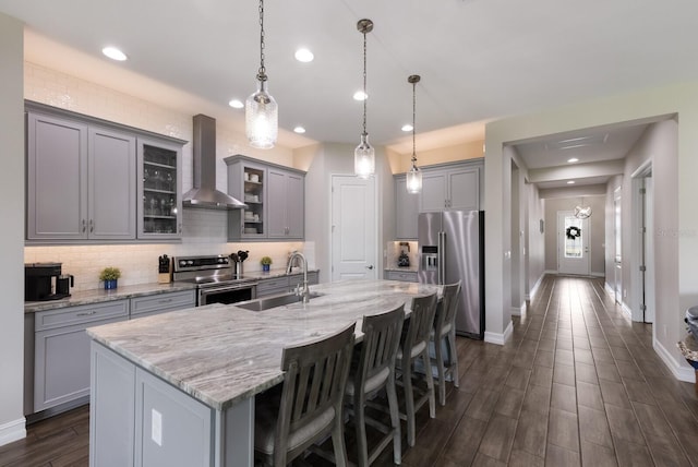 11513 11th Ave E, Bradenton, FL 34212 - kitchen featuring appliances with stainless steel finishes, wall chimney range hood, a sink, gray cabinetry, and tasteful backsplash