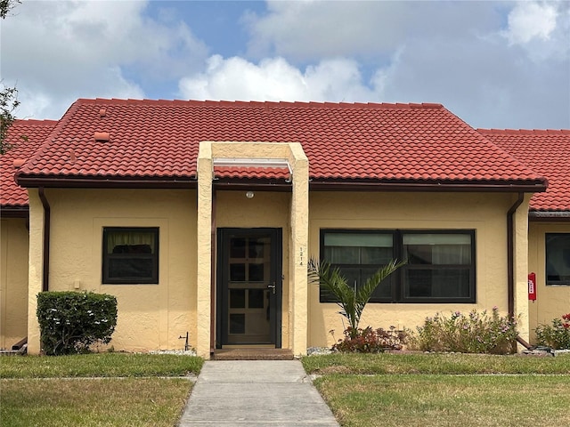 1214 56th St W Unit 1214, Bradenton, FL 34209 - view of front of house with stucco siding, a tiled roof, and a front yard