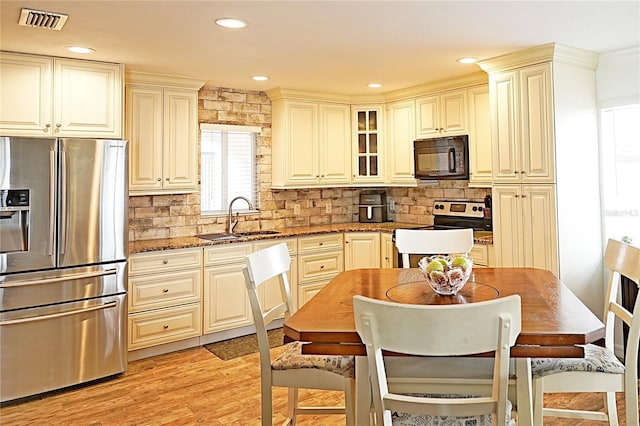 kitchen with appliances with stainless steel finishes, a sink, dark stone countertops, decorative backsplash, and recessed lighting