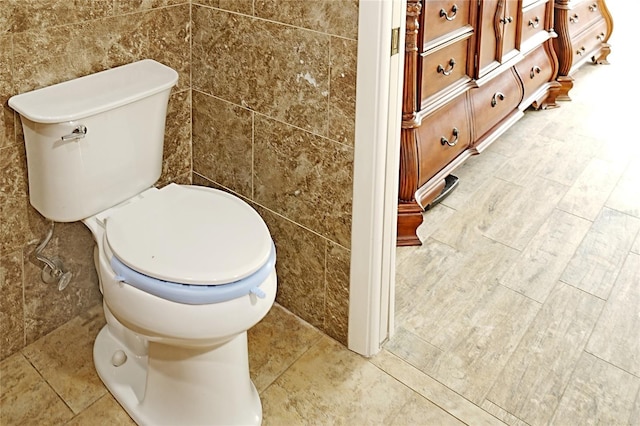 bathroom with toilet and tile walls