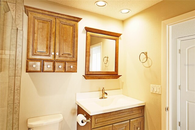 full bathroom with toilet, vanity, and a textured ceiling
