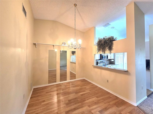 7201 29th Avenue Dr W Unit 306, Bradenton, FL 34209 - unfurnished dining area with a chandelier, lofted ceiling, wood finished floors, a textured ceiling, and baseboards