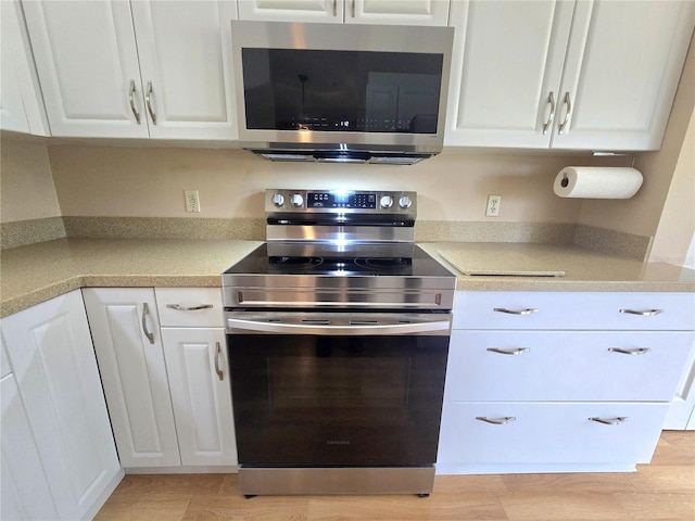 7201 29th Avenue Dr W Unit 306, Bradenton, FL 34209 - kitchen with stainless steel appliances, white cabinetry, light countertops, and light wood finished floors