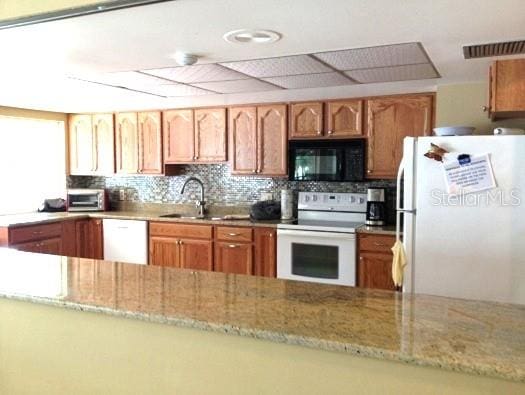 7201 29th Avenue Dr W Unit 306, Bradenton, FL 34209 - kitchen with white appliances, light stone counters, backsplash, and a sink