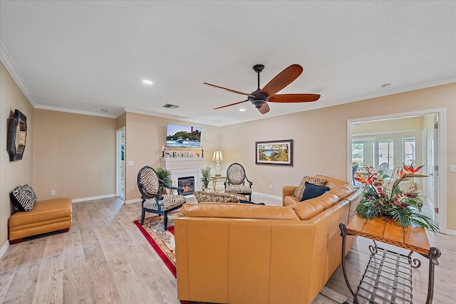 1432 Colony Pl, Venice, FL 34292 - living room featuring a glass covered fireplace, a ceiling fan, light wood-style floors, baseboards, and ornamental molding