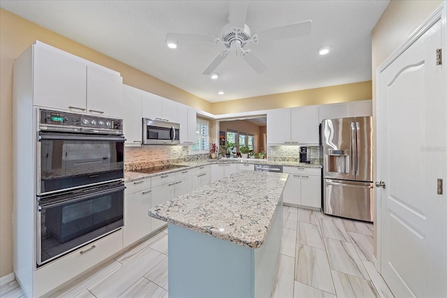 1432 Colony Pl, Venice, FL 34292 - kitchen featuring black appliances, a center island, tasteful backsplash, a ceiling fan, and white cabinets