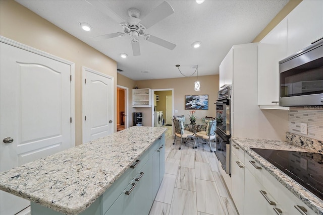 1432 Colony Pl, Venice, FL 34292 - kitchen with black appliances, a ceiling fan, a kitchen island, white cabinetry, and tasteful backsplash