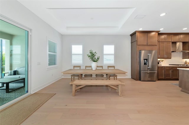 dining space with recessed lighting, light wood finished floors, and a raised ceiling