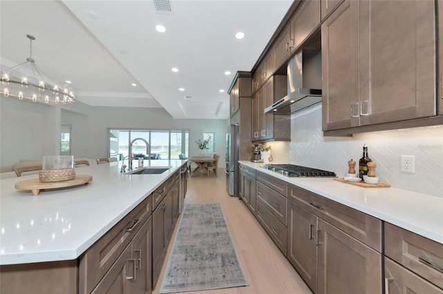 kitchen featuring a sink, appliances with stainless steel finishes, exhaust hood, light countertops, and recessed lighting
