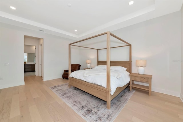 bedroom featuring recessed lighting, a tray ceiling, light wood-type flooring, and baseboards