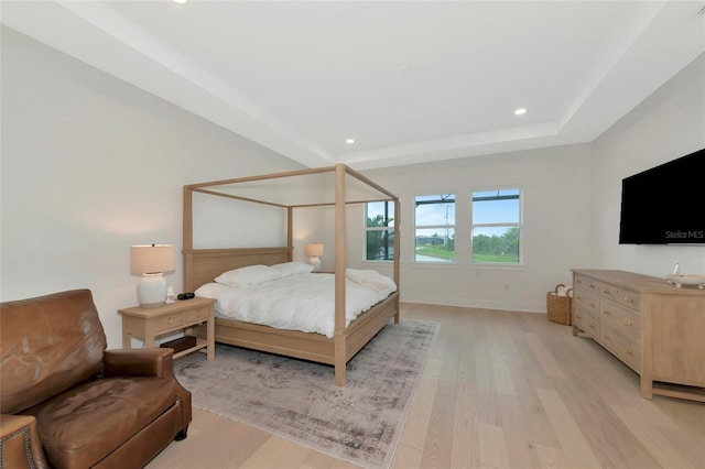 bedroom featuring light wood-type flooring, recessed lighting, baseboards, and a raised ceiling