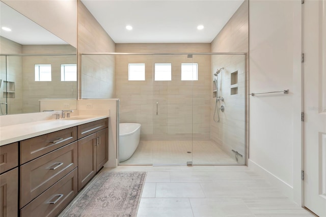 bathroom with healthy amount of natural light, a stall shower, vanity, a freestanding bath, and recessed lighting