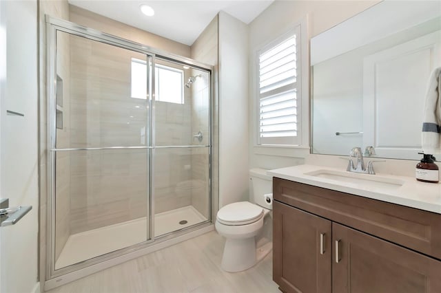 bathroom with a stall shower, toilet, and vanity