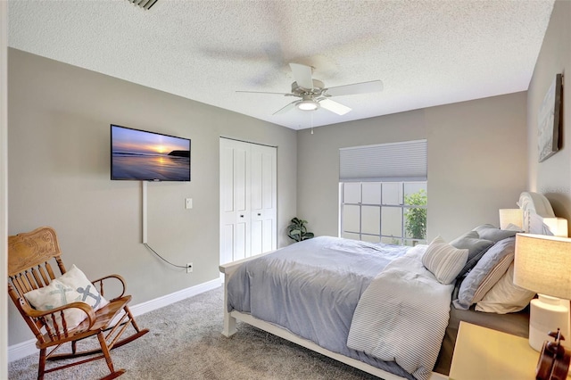 carpeted bedroom with a closet, baseboards, a ceiling fan, and a textured ceiling