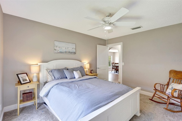 bedroom featuring light colored carpet, baseboards, arched walkways, and a ceiling fan