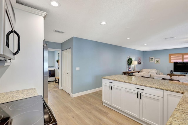 kitchen featuring light wood-type flooring, open floor plan, white cabinets, black electric range, and stainless steel microwave