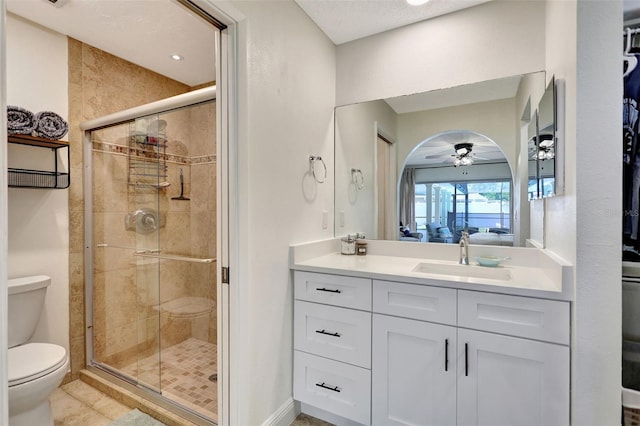 bathroom with a shower stall, toilet, ceiling fan, and vanity