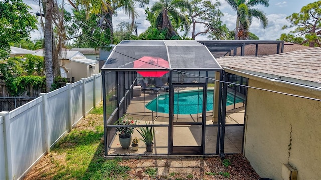 view of swimming pool featuring a fenced backyard, a patio, and glass enclosure