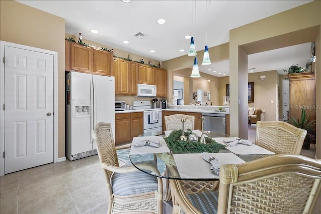 13180 SW Pembroke Cir N, Lake Suzy, FL 34269 - kitchen with white appliances, light countertops, hanging light fixtures, brown cabinetry, and light tile patterned flooring