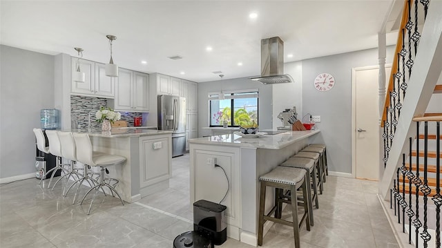 kitchen featuring island exhaust hood, a peninsula, stainless steel refrigerator with ice dispenser, a breakfast bar, and recessed lighting