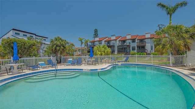 community pool featuring fence, a patio area, and a residential view