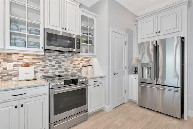 5561 Cannes Cir Unit 5101, Sarasota, FL 34231 - kitchen with stainless steel appliances, backsplash, ornamental molding, white cabinetry, and light wood-style flooring