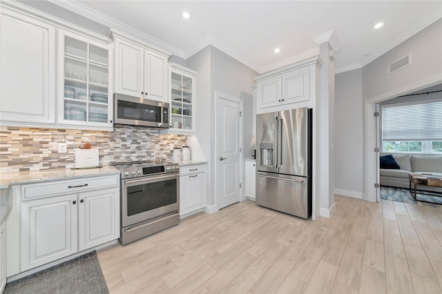 5561 Cannes Cir Unit 5101, Sarasota, FL 34231 - kitchen featuring appliances with stainless steel finishes, crown molding, backsplash, white cabinets, and baseboards
