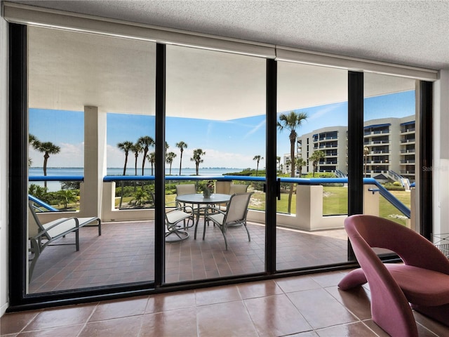 2120 Harbourside Dr Unit 617, Longboat Key, FL 34228 - doorway to outside with a water view, tile patterned flooring, floor to ceiling windows, and a textured ceiling
