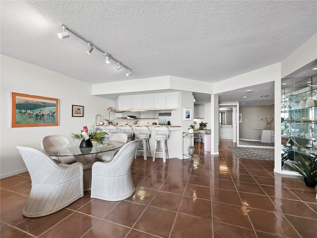 2120 Harbourside Dr Unit 617, Longboat Key, FL 34228 - dining space featuring dark tile patterned flooring, a textured ceiling, rail lighting, and baseboards