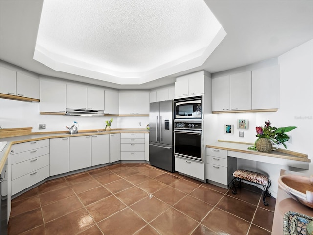 2120 Harbourside Dr Unit 617, Longboat Key, FL 34228 - kitchen with appliances with stainless steel finishes, a raised ceiling, light countertops, a textured ceiling, and dark tile patterned floors