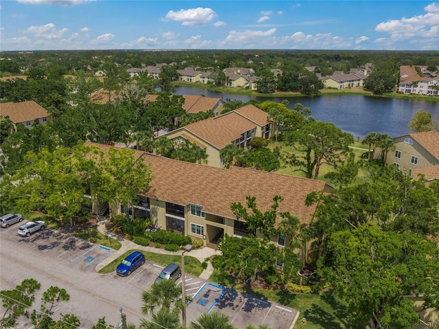 aerial view of residential area featuring a large body of water and a tree filled landscape